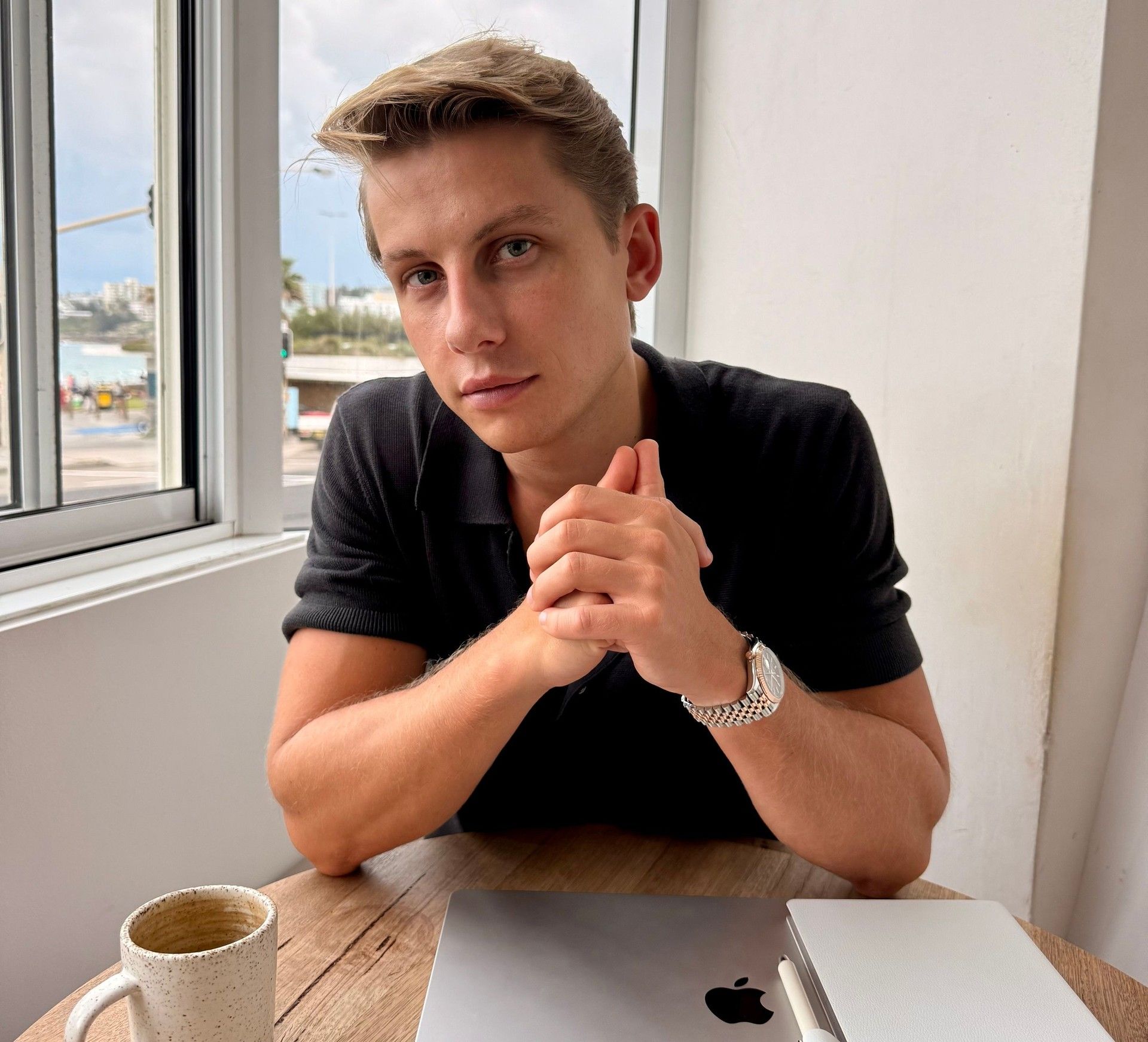 Adam Love sitting at a cafe table with a laptop and coffee
